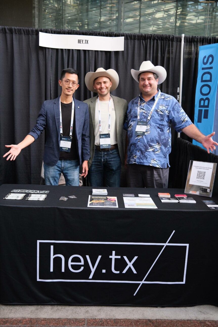 Three Handshake community members together at the Hey.tx booth